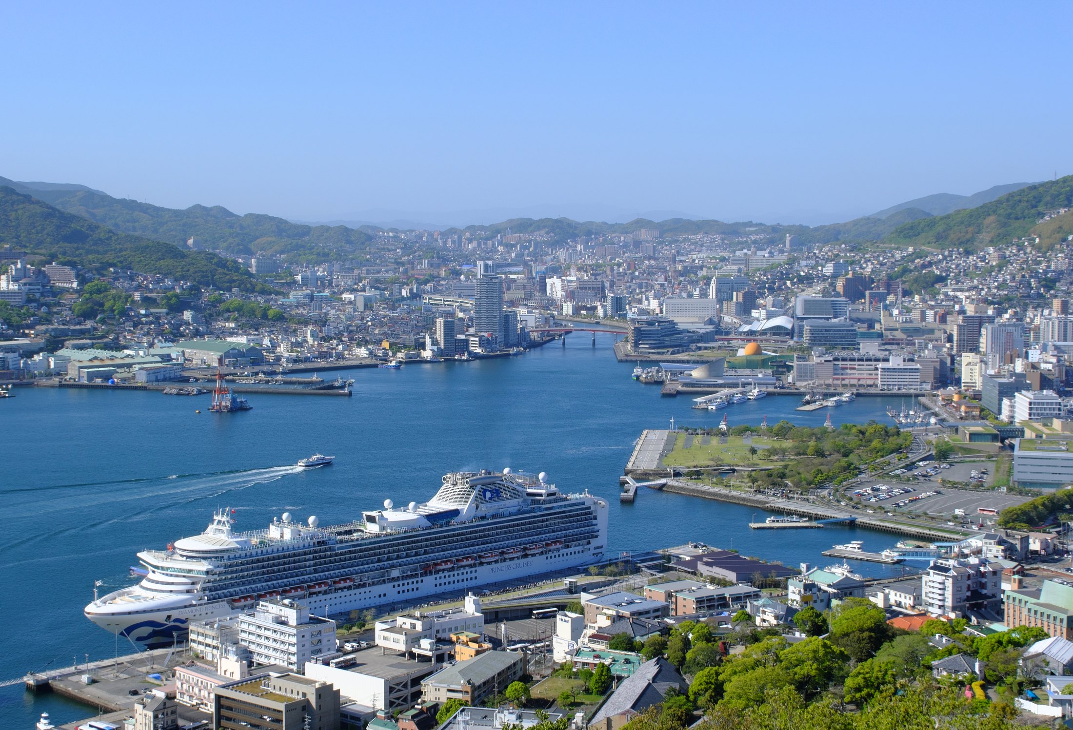 長崎港を見下ろす実写風景。港と市街地、山並みが広がる