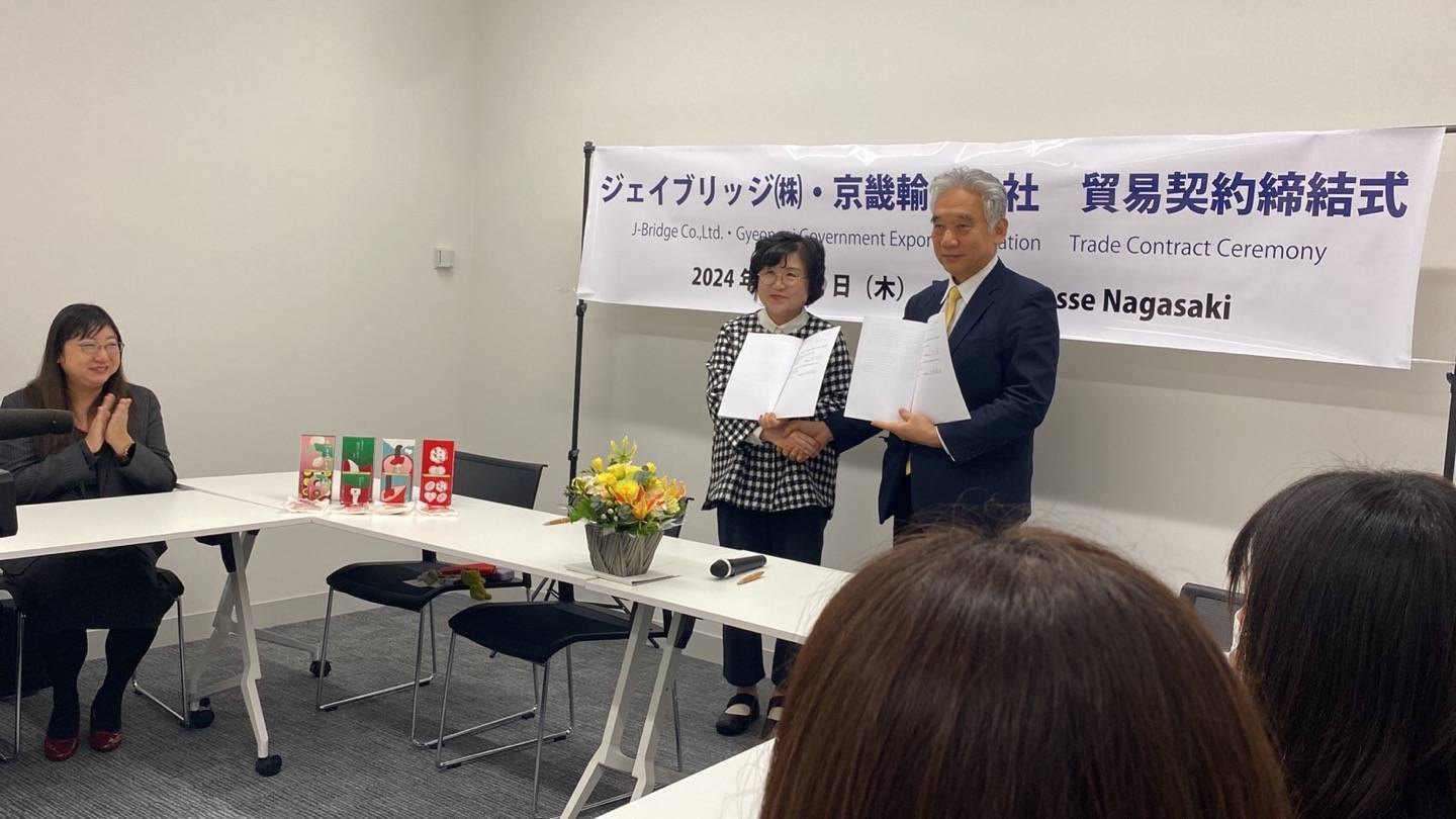 ジェイブリッジと韓国貿易公社の貿易契約締結式で契約書を掲げる様子